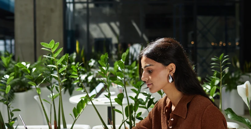 Profissional trabalhando em ambiente corporativo com plantas.